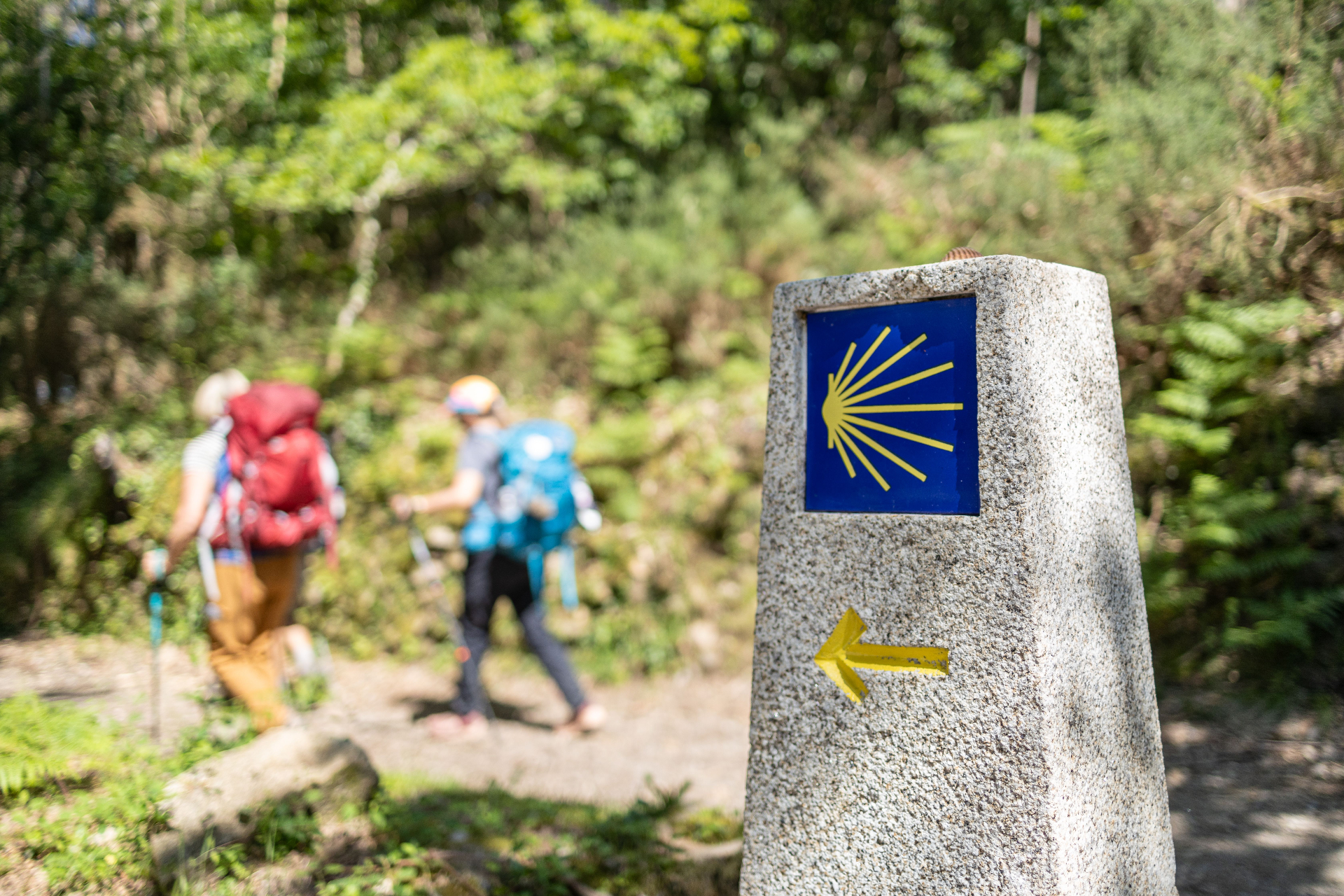 Mojón del Camino de Santiago con peregrino caminando hacia Fisterra y Muxía en Galicia
